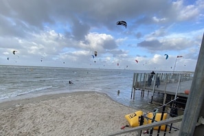 Ein Strand mit einer Mole, Drachen und einem Rettungsschwimmerstand.