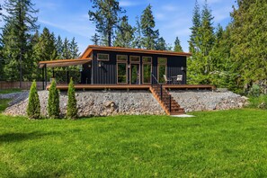 Eine moderne Hütte mit einer Holzterrasse, einer Treppe und Blick auf den umliegenden Wald.