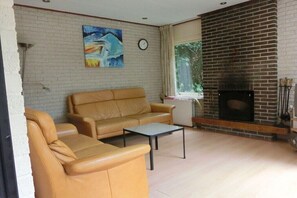 Ein Wohnzimmer mit Kamin aus Backstein, einer Couch, einem Couchtisch und einem Bild an der Wand.