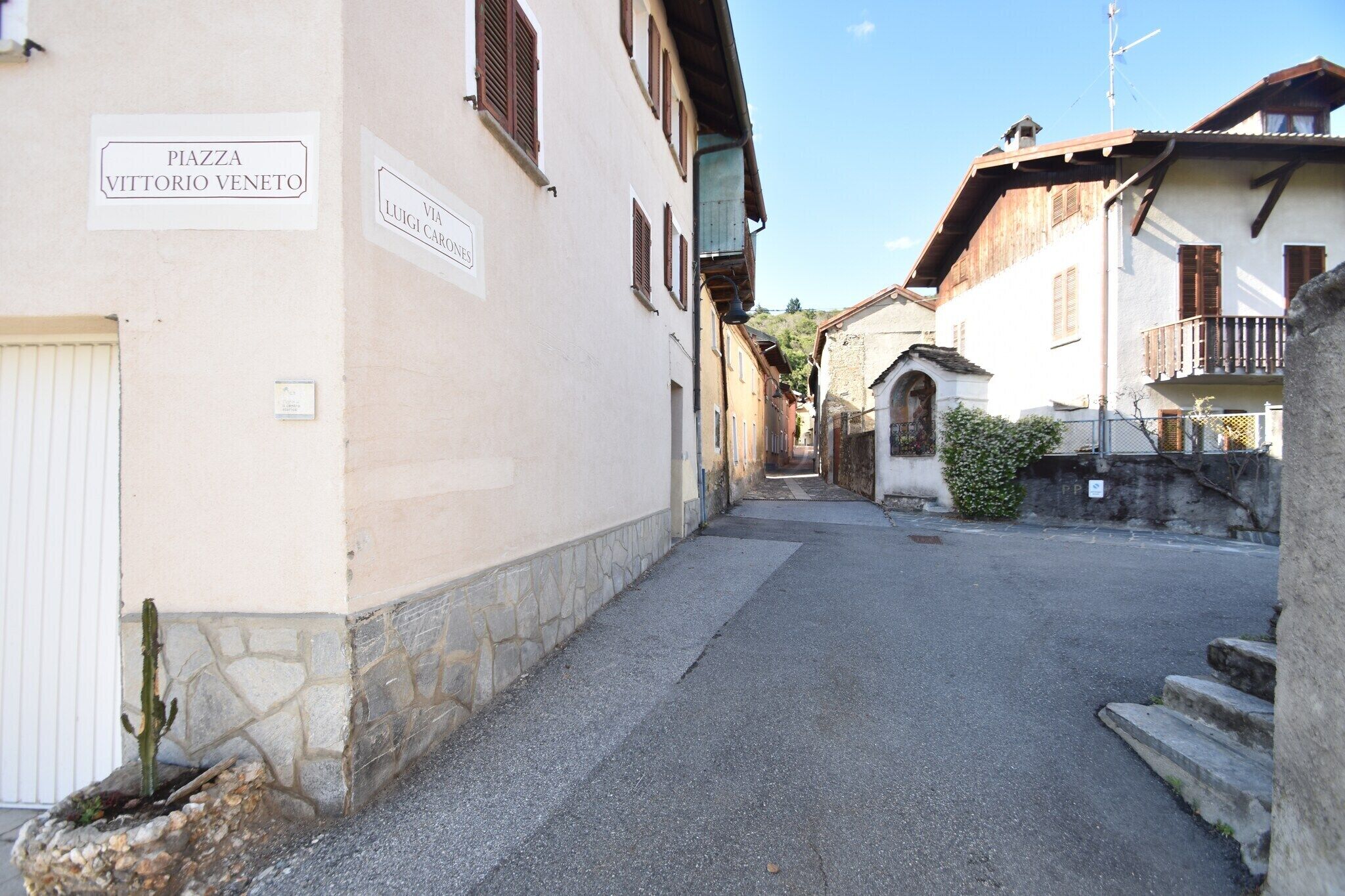 Una calle estrecha flanqueada por edificios, con indicaciones que señalan 'PIAZZA VITTORIO VENETO' y 'VIA LUIGI CARONES'.