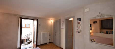 A bedroom with a bed, a radiator, a door leading to a balcony, and a mirror with pictures.