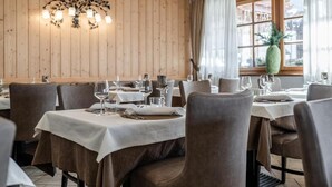 Un restaurante con paredes de madera, mesas dispuestas con manteles blancos y sillas.