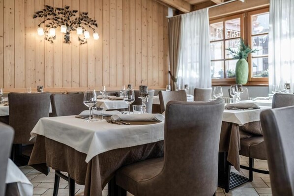 Un restaurant aux murs en bois, avec des tables recouvertes de nappes blanches et des chaises.