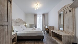 Un dormitorio con cama, mesita de noche, cómoda, espejo y escritorio.