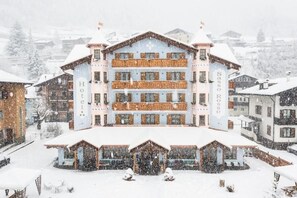 A multi-story hotel with balconies, a central entrance, and a snowy environment.