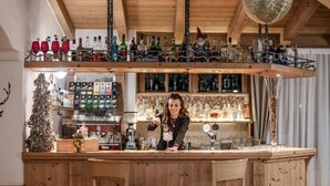 Un área de bar con mobiliario de madera, un árbol de Navidad y varias botellas en estantes.