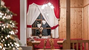 Un comedor con una mesa de madera, sillas y un árbol de Navidad.
