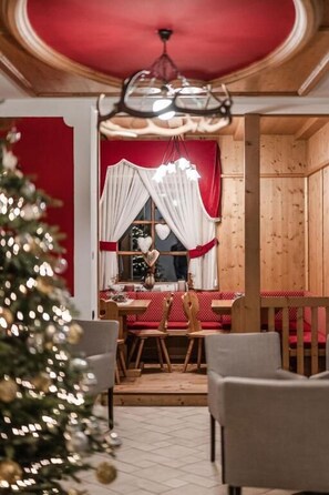 A dining area with a wooden table, chairs, and a Christmas tree.