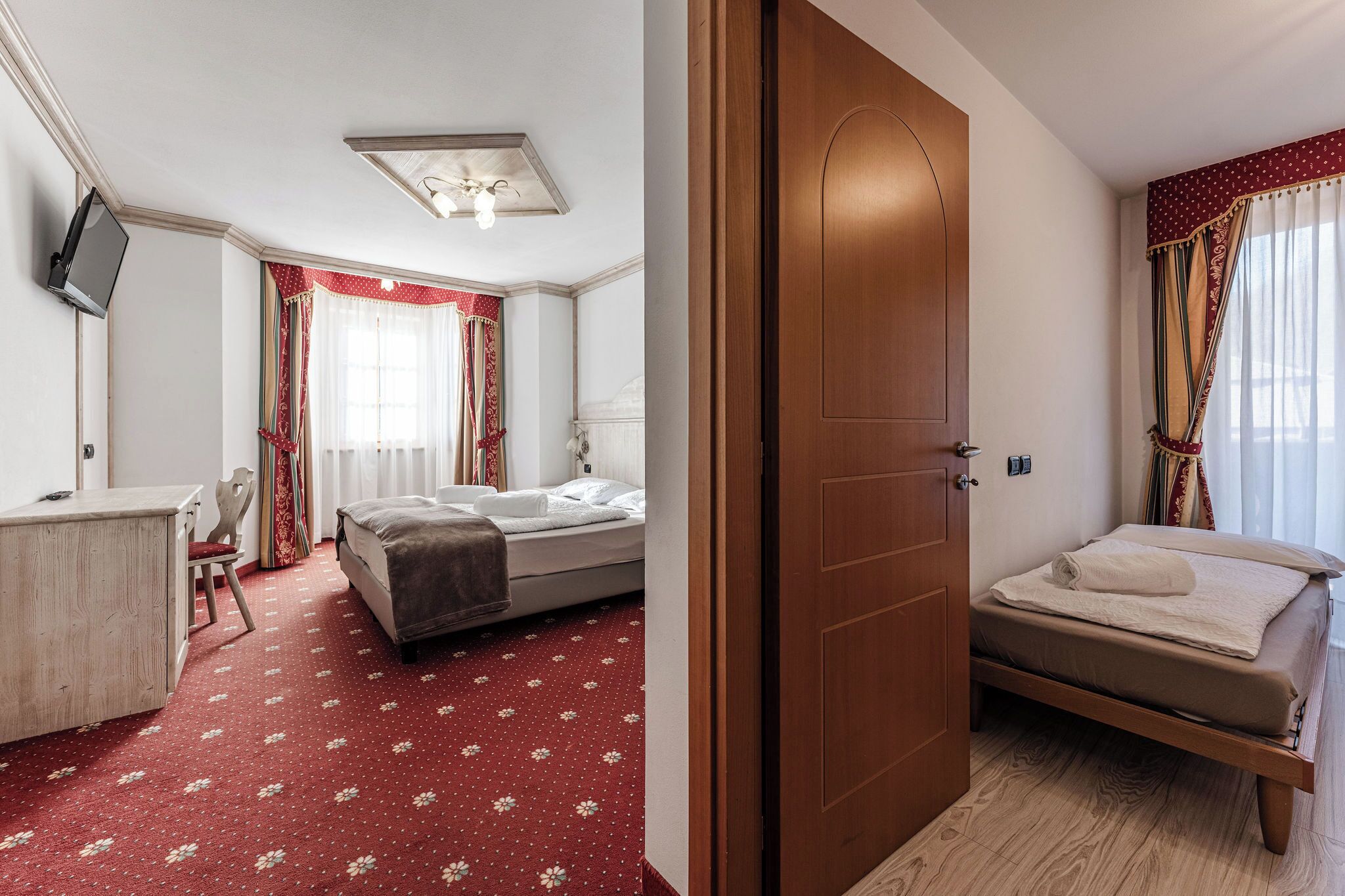 Una habitación de hotel con cama, escritorio, silla y televisor.