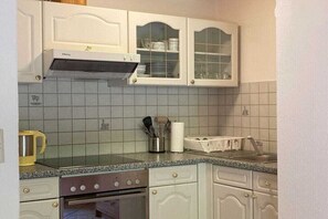A kitchen with white cabinets, a stove, and a microwave. - Holiday apartment Vogelnest (Hippach)