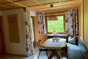 A cozy room with a wooden ceiling, a dining table with chairs, a sofa, and a window with curtains. - Holiday apartment Vogelnest (Hippach)