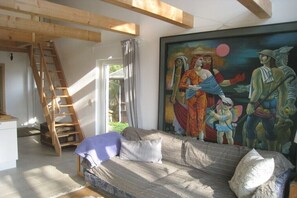 Ein Zimmer mit einer Holzleiter, einem Sofa und einem großen Gemälde an der Wand.