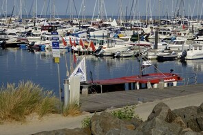 Ein Yachthafen mit zahlreichen vertäuten Booten, eine Holzsteganlage und ein Schild, das auf einen Fischzone hinweist.
