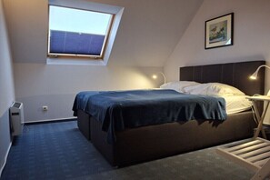 Ein Schlafzimmer mit einem Bett, einem Oberlicht, einem Nachttisch, einer Lampe und einem Bild an der Wand.