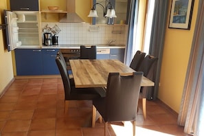 Eine kleine Küche mit Esstisch und Stühlen, einem Kühlschrank, einem Herd und einer Spüle.