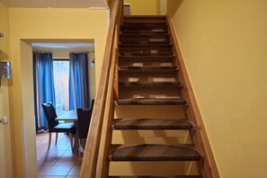 Eine Holztreppe mit gepolsterten Stufen führt zu einem Essbereich mit Tisch und Stühlen.