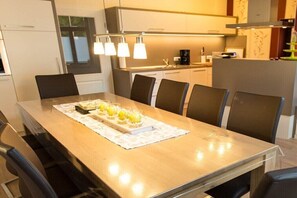 A modern kitchen with a dining table, chairs, and a coffee maker. - Holiday home in Malchow with swimming pool (Malchow)
