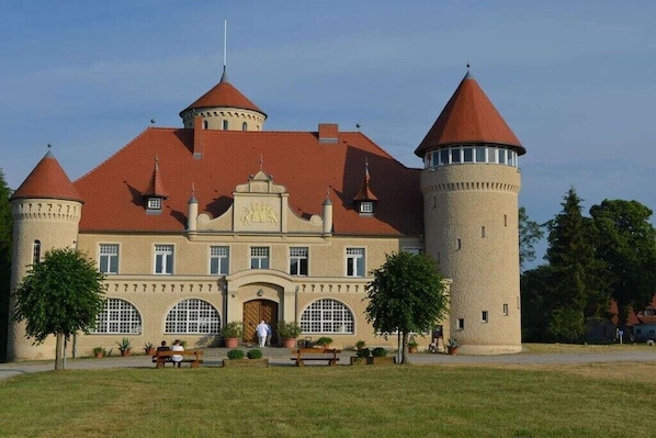 A castle-like building with a central tower, arched windows, and a red-tiled roof. - Holiday home in Stolpe with swimming pool (Stolpe)
