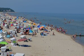 A beach with numerous beach chairs and umbrellas, a pier in the background, and a clear sky. - Holiday home in Stolpe with swimming pool (Stolpe)