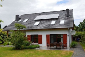 A house with a sloped roof, solar panels, a satellite dish, and a garden with a patio. - Holiday home in Stolpe with swimming pool (Stolpe)