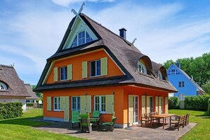A house with a steep gabled roof, a front porch with chairs, and a small table. - Holiday apartment in Glowe with swimming pool (Glowe)