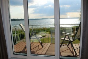 Ein Balkon mit Seeblick, zwei Stühle und einem Geländer.