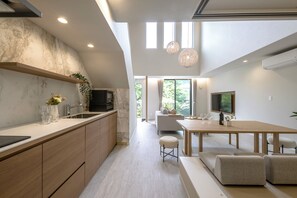 A modern kitchen with a marble backsplash, wooden cabinets, and a dining area with a large table and seating. - Stagione Hakone Sengokuhara Vento (Ashigarashimo gun Hakone-machi)
