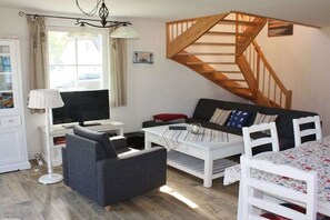 A living room with a sofa, a coffee table, a TV, a lamp, and a staircase. - Godewind on the Baltic Sea (Glowe)