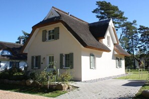 A two-story house with a steeply pitched roof, a small front porch, and a paved driveway. - Godewind on the Baltic Sea (Glowe)
