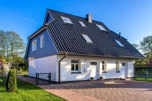Ein zweistöckiges Haus mit schrägem Dach, einer Haustür und einem kleinen Vorgarten.