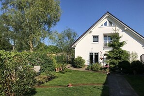 Ein zweistöckiges Haus mit Vordergarten, einem sichtbaren Balkon und einem Weg zum Eingang.