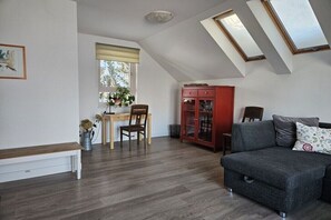 Quarto no estilo loft com sofá, mesa de jantar com cadeiras, armário e claraboias.