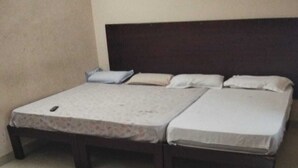 Una habitación con dos camas, un cabecero de madera y suelo de baldosas.