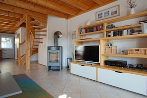 Ein modernes Wohnzimmer mit Kamin, Holzbücherregalen, einem Flachbildfernseher und einer Treppe.