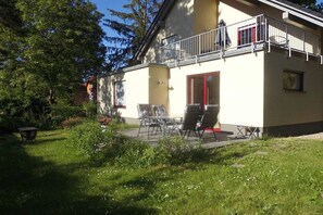 Un bâtiment à deux étages doté d’un balcon, d’un espace extérieur aménagé pour s’asseoir et d’un jardin.