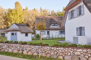 Eine Reihe von Häusern mit Steinmauern, einer Grünfläche und Bäumen im Hintergrund.