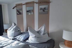 Ein Schlafzimmer mit Bett, Kissen, einer Lampe und Bildern an der Wand.