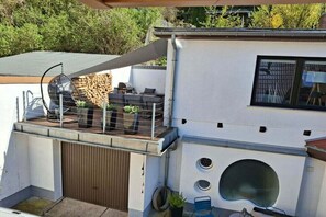 Ein modernes Haus mit Balkon, Grill und großem Fenster.