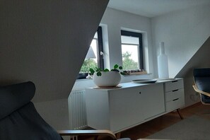 Ein modernes Zimmer mit einem weißen Schrank, einer Topfpflanze und einem Sessel.