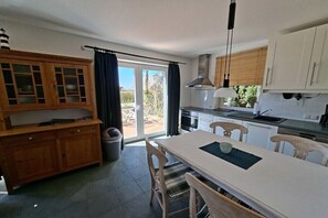 Eine moderne Küche mit Essbereich, großen Fenstern und Blick ins Freie.