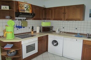 Eine kompakte Küche mit Mikrowelle, Toaster, Kaffeemaschine, Backofen und Waschmaschine.