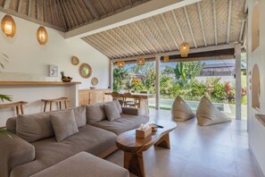 A spacious living area with a sofa, coffee table, and hanging lights. - 1BR Romantic Getaway in Ubud, Villa Lojo with Private Pool (Gianyar)
