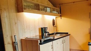 A kitchen with wooden cabinets, a black countertop, a coffee maker, and a sink. - Holiday Home in Noord-scharwoude With Wi-fi (Noord-Scharwoude)