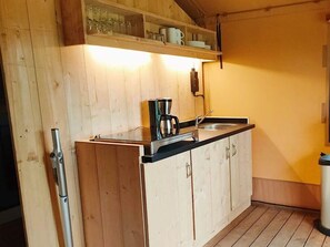 Eine Küche mit Holzschränken, einer schwarzen Arbeitsplatte, einer Kaffeemaschine und einem Spülbecken.