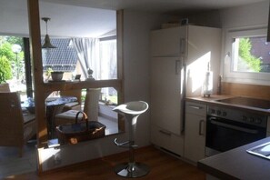 Eine kleine Küche mit Kühlschrank, Backofen und einem Essbereich mit Tisch und Stühlen.