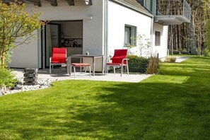 Ein modernes Haus mit Terrasse, Gartenmöbeln und einem gepflegten Rasen.