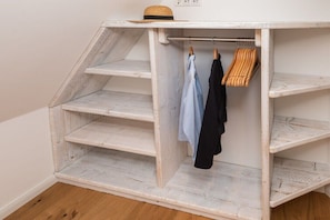 Ein weißes Holzregal mit daraufhängender Kleidung.