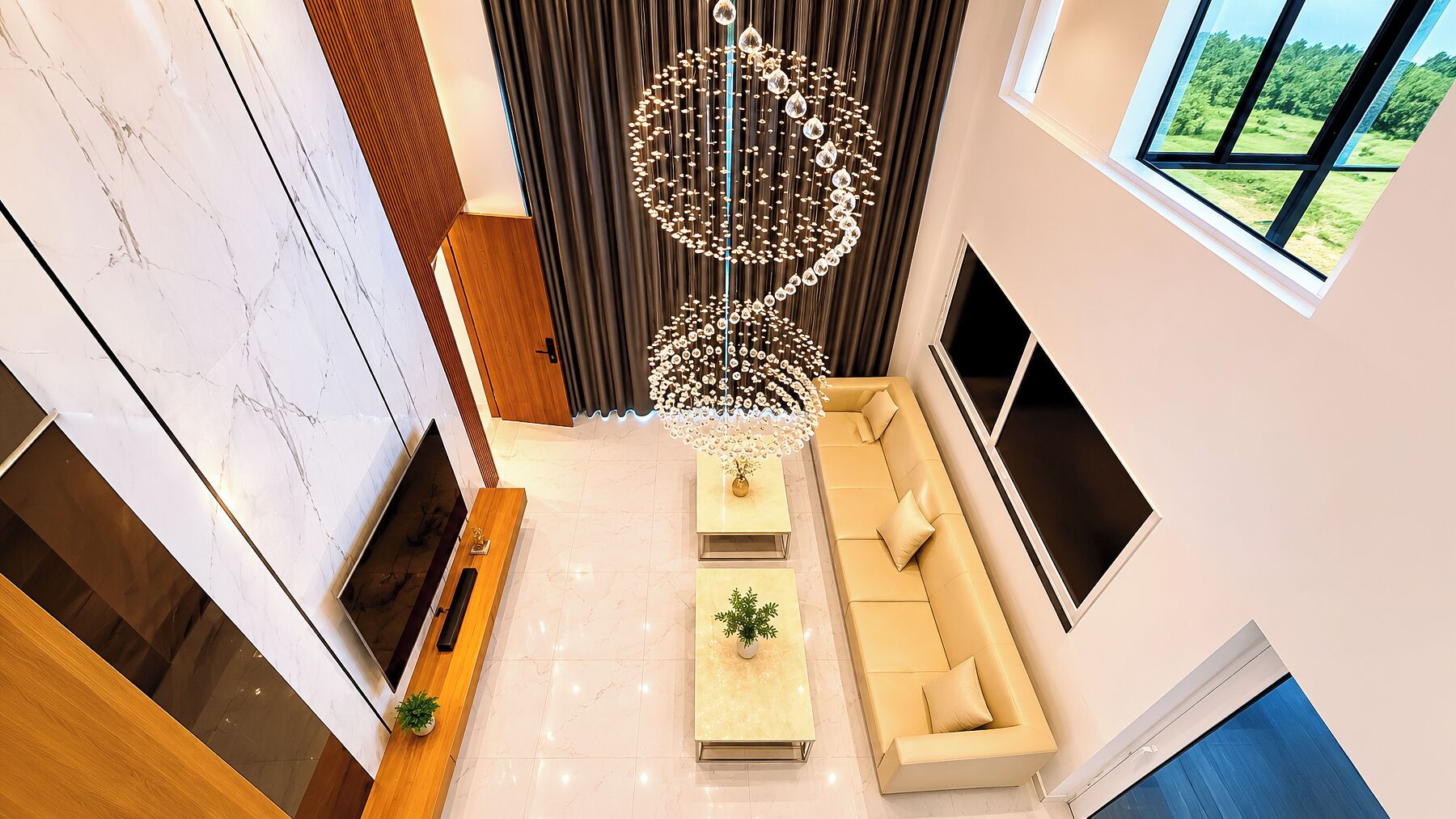 A modern living room with a large window, a chandelier, a sofa, and a TV.