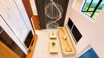A modern living room with a large window, a chandelier, a sofa, and a TV.