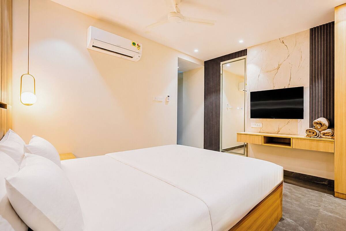 Una habitación de hotel con una cama, televisión, aire acondicionado y un armario de madera.
